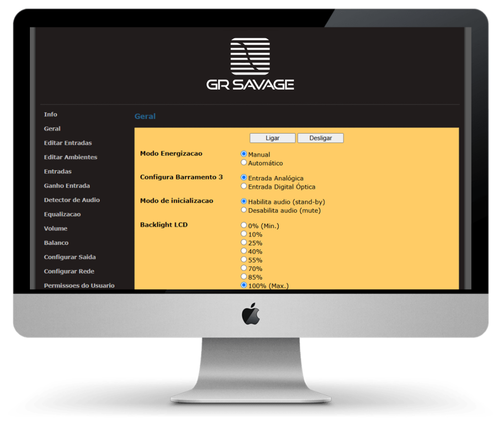 Monitor de computador exibe a interface de configuração via Web de um Multiroom Savage. A tela mostra o menu "Geral" com opções de modo de energização, configuração de barramentos, modo de inicialização e controle de brilho do LCD (Backlight). À esquerda, uma lista completa de menus técnicos como Equalização, Ganho de Entrada e Configuração de Rede.